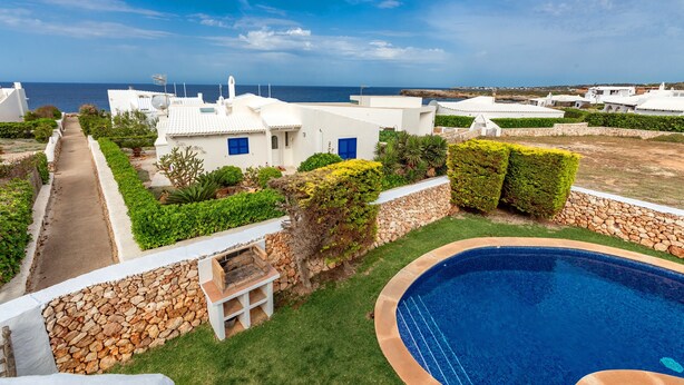 A residential area with white houses, a swimming pool, and a view of the sea. - Charming Holiday Home with Sea Views, Private Pool and Wi-Fi (Binibèquer)