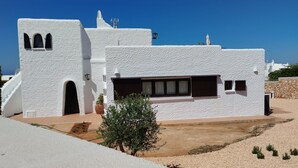 A white building with a flat roof, a small arched window, and a rectangular window. - Charming Holiday Home with Sea Views, Private Pool and Wi-Fi (Binibèquer)
