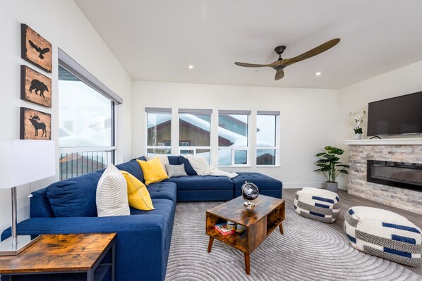 A modern living room with a blue sectional sofa, a wooden coffee table, and a fireplace.