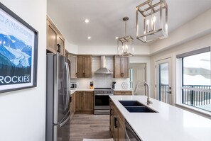 A modern kitchen with wooden cabinets, stainless steel appliances, and pendant lighting.