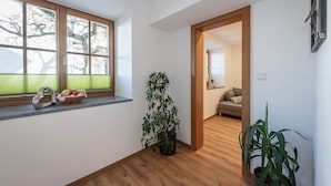 Un pasillo con una ventana, una planta en maceta y una puerta que da a una habitación.