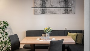 Un comedor con una mesa de madera, sillas negras, un sofá gris y un cuadro abstracto colgado en la pared.
