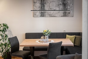 Et spiseområde med et træbord, sorte stole, en grå sofa og et abstrakt maleri på væggen.