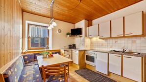 A compact kitchen with wooden cabinets, a built-in oven, and a dining area with a bench and table. - Apartment 'Wohnung Elstar Schnalserhof' with Mountain View, Shared Terrace and Wi-Fi (Latsch)