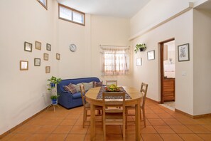A dining area with a round table, chairs, a clock, and a blue sofa.