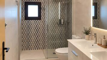 Un baño moderno con ducha, inodoro y tocador.