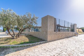 Un espace extérieur aménagé avec un revêtement pavé, un mur en pierre, une clôture en métal et un arbre.