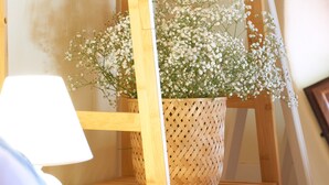 A bed with a wooden headboard, a bedside lamp, and a potted plant with white flowers. - Holiday Home 'Casa Degli Ulivi' with Private Terrace and Wi-Fi (Marzamemi)