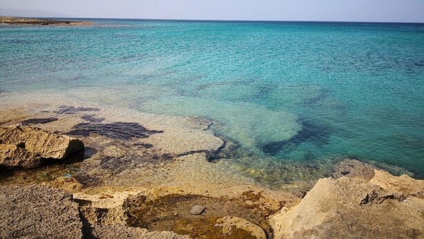 A coastal landscape with clear turquoise water, rocky formations, and a distant shoreline. - Holiday Home 'Casa Degli Ulivi' with Private Terrace and Wi-Fi (Marzamemi)