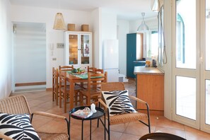 Un coin repas comprenant une table, des chaises et une petite table d’appoint sur laquelle se trouve un livre.