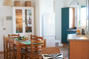 Una cocina con una mesa de comedor, sillas, un refrigerador y un armario.