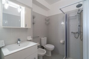 Un baño con lavamanos, inodoro, bidé y ducha.