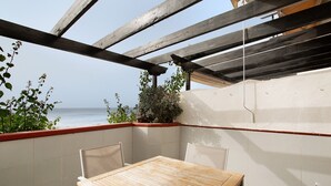 Ein Holztisch mit Stühlen in einer Ecke, mit Blick auf das Meer.