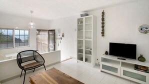 Ein Wohnzimmer mit Fernseher, weißem Schrank und einem Sessel.