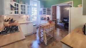 Una cocina con armarios blancos, una estufa a gas, un lavamanos y una mesa de madera.