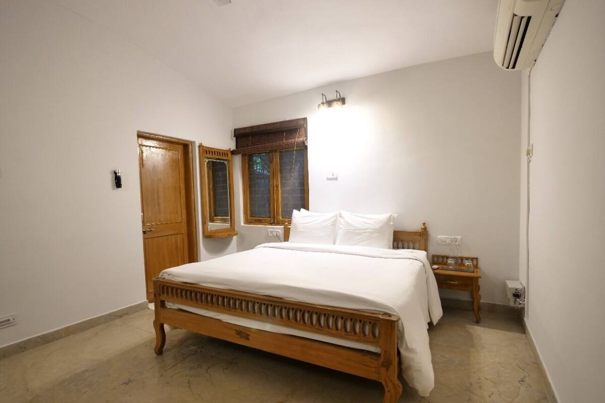 Un dormitorio con cama de madera, una mesita de noche de madera, un armario de madera y una ventana con persianas.