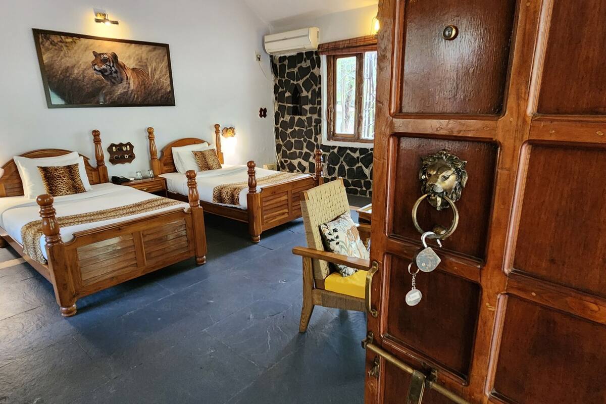 Una habitación con dos camas de madera, una pared de piedra, un cuadro de un perro y un llamador de león.