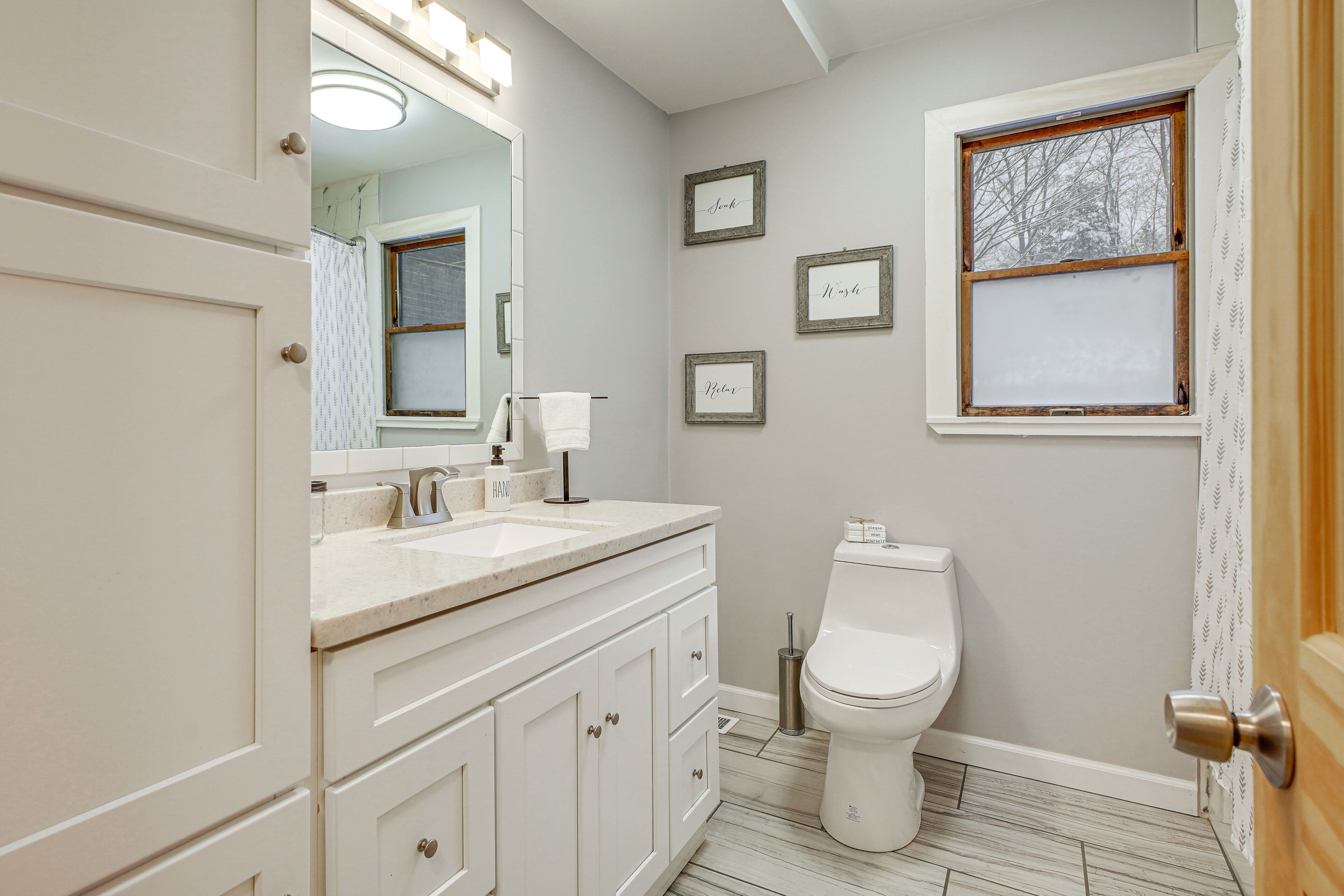 Une salle de bain avec un meuble-lavabo blanc, des toilettes et une fenêtre en verre dépoli.