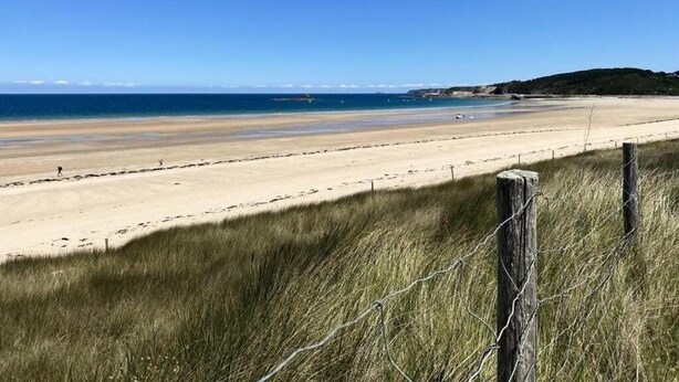 A beach with a wooden fence and grassy dunes in the foreground. - 4-person apartment near the beach in Sables-d’Or-les-Pins | Ref 107 (FREHEL)
