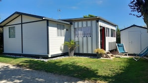 A mobile home with a small attached garage, a covered porch, and a gravel driveway. - Charming chalet located in a 4-star  campsite - 6 people (GUIDEL-PLAGES)