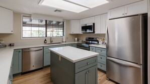A modern kitchen with a central island, stainless steel appliances, and light-colored cabinetry. - Mingus Mountain Vista: Views, Shopping, Relaxation. 20 Minutes to Sedona  (Cottonwood)