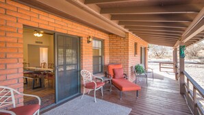 A covered patio with a brick wall, sliding glass doors leading to a dining area, and outdoor seating with chairs and a table. - Mingus Mountain Vista: Views, Shopping, Relaxation. 20 Minutes to Sedona  (Cottonwood)