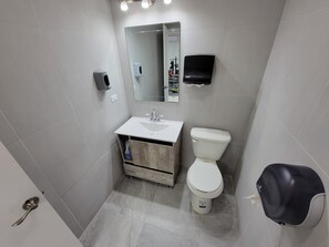 Ein modernes Badezimmer mit einem weißen Waschbecken, einer Toilette und einem Spiegel.