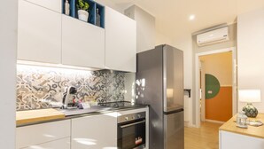 Cocina moderna con armarios blancos, refrigerador de acero inoxidable, horno empotrado y un salpicadero con diseño.