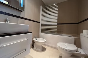 Une salle de bain moderne équipée d’un lavabo, d’un bidet, de toilettes et d’une douche à parois de verre.