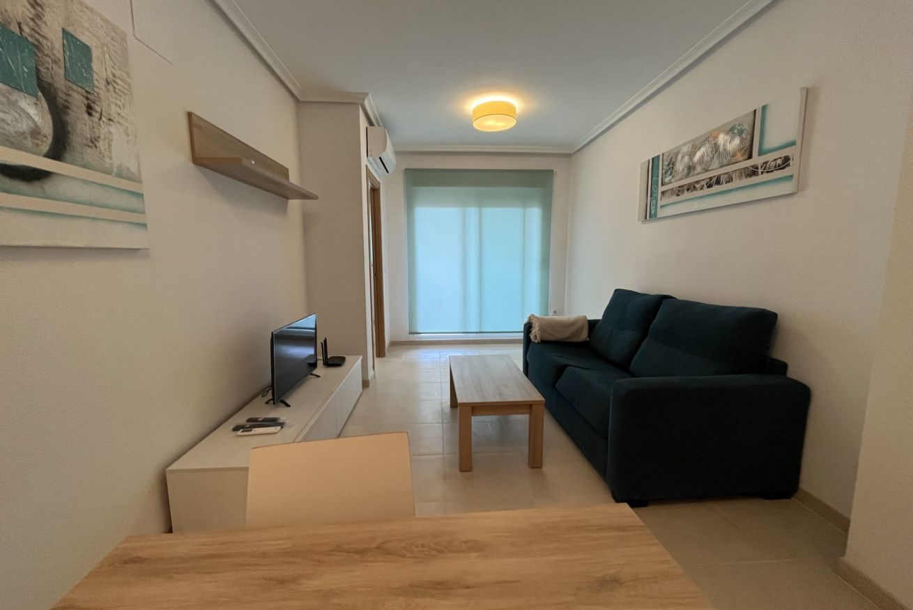 Una sala de estar moderna con un sofá, una mesa de centro y un televisor sobre un mueble.