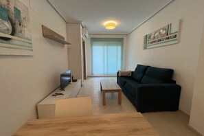 A modern living room with a sofa, a coffee table, and a TV on a stand.