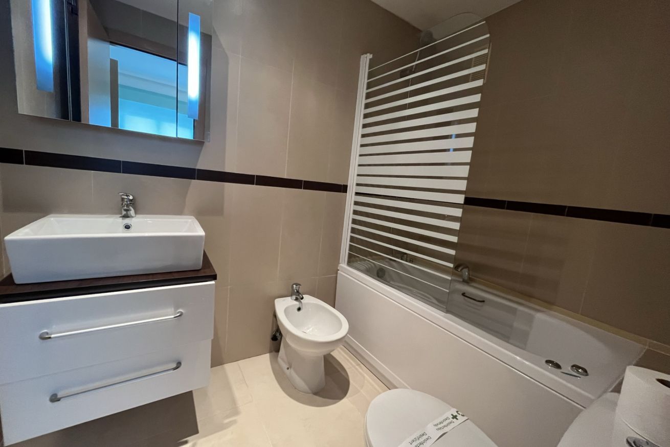 Une salle de bain moderne équipée d’un lavabo, d’un bidet, de toilettes et d’un grand miroir.