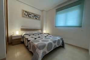 Une chambre à coucher comprenant un lit, des tables de chevet, une œuvre d’art murale et une fenêtre.