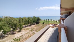 A view from a balcony overlooking a beach with palm trees and a clear sky.