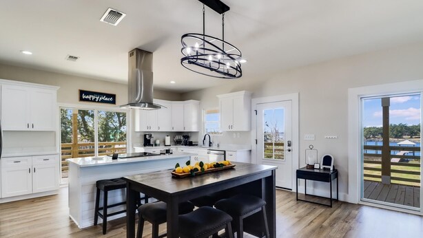 Una cocina moderna con una isla central, armarios blancos y un cartel que dice 'lugar feliz'.