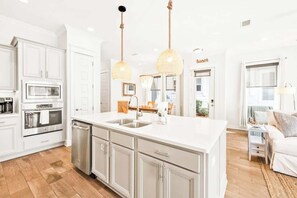 A spacious kitchen with white cabinetry, stainless steel appliances, and a large island with a sink.