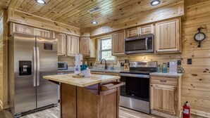 A modern kitchen with wooden cabinets, stainless steel appliances, and a central island. - Hilltop Hideaway - 3 Bedroom 2 Bath - Private! (Sevierville)
