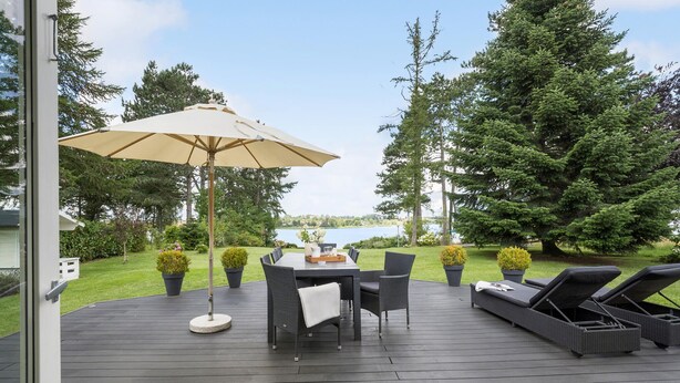 A deck with a table and chairs, a lounge chair, and a large umbrella.