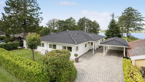 A two-story house with a covered porch, a paved driveway, and a small garden.