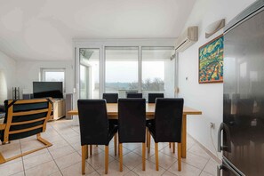 A modern dining area with a large table and chairs, a television, and a refrigerator. - Holiday apartment mit Klimaanlage (Umag)