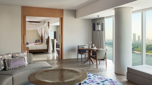 A modern hotel room with a large bed, a sitting area with a coffee table, and a dining table with chairs. There is a large window offering a city view. - Marriott Marquis Dubai Creek (Dubai)