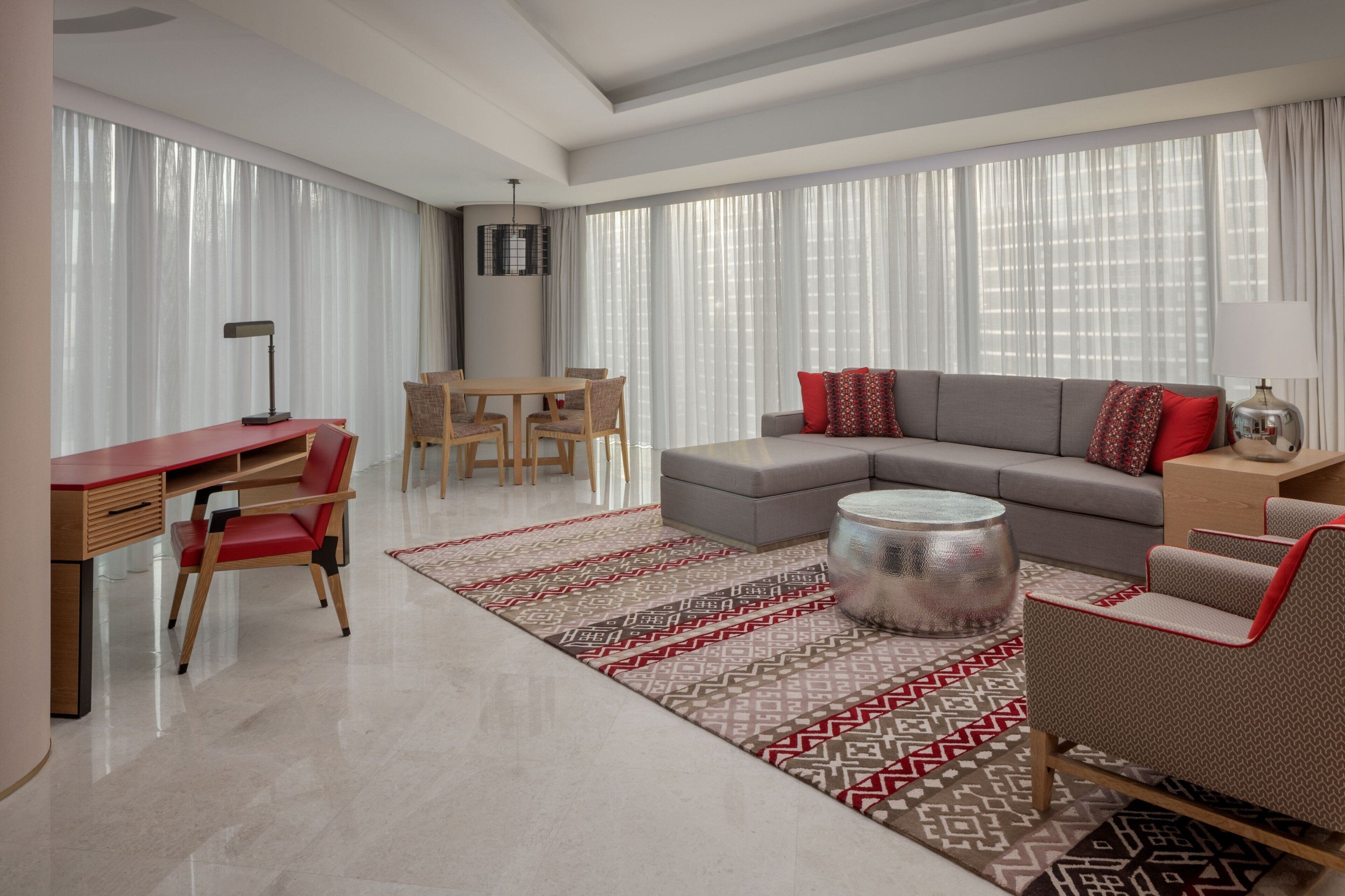 A modern living room with a sofa, coffee table, and a dining area with chairs and a table.
