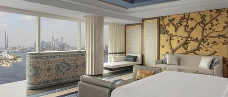 A modern hotel room with a large bed, a sofa, and a seating area by a window overlooking a cityscape.