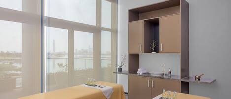 Une chambre d’hôtel avec deux lits, une petite kitchenette et une grande fenêtre donnant sur un paysage urbain.