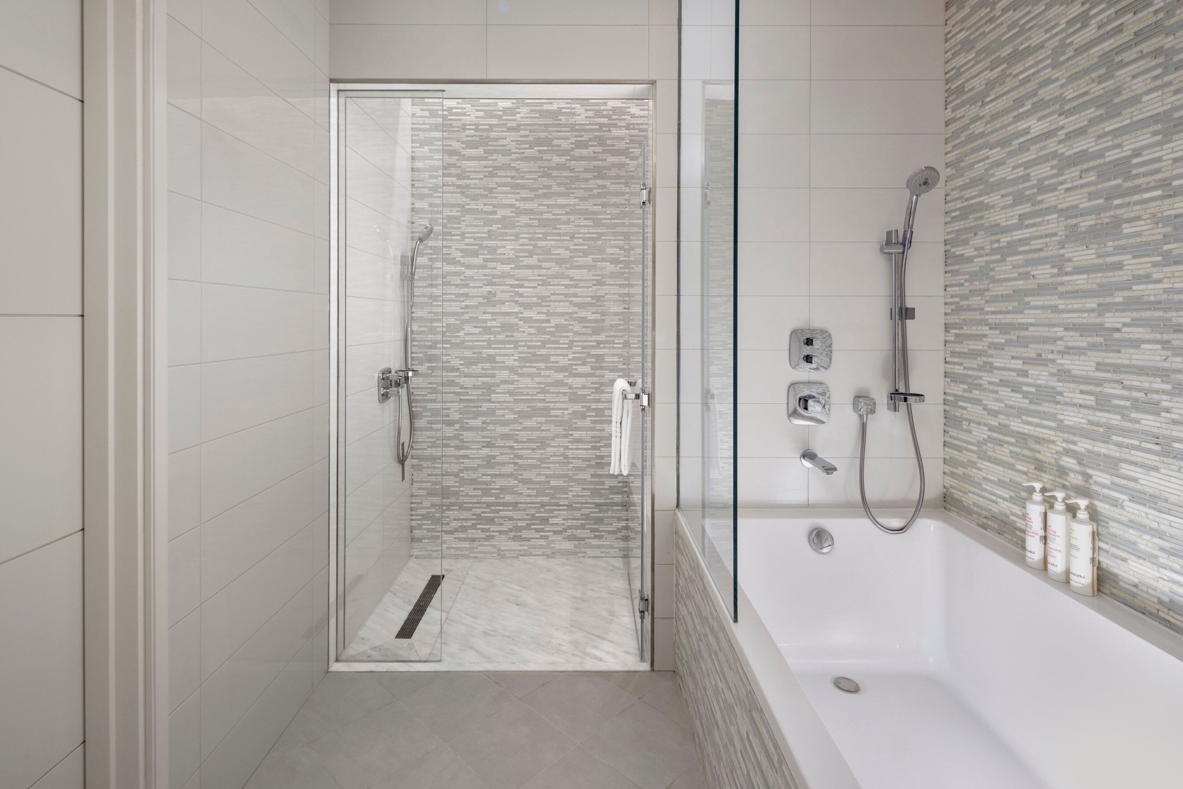 Un baño moderno con ducha envuelta en vidrio, bañera independiente y zona de ducha azulejada.