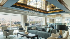 A spacious living room with a large sofa, armchairs, a coffee table, and a view of the city. - Marriott Marquis Dubai Creek (Dubai)