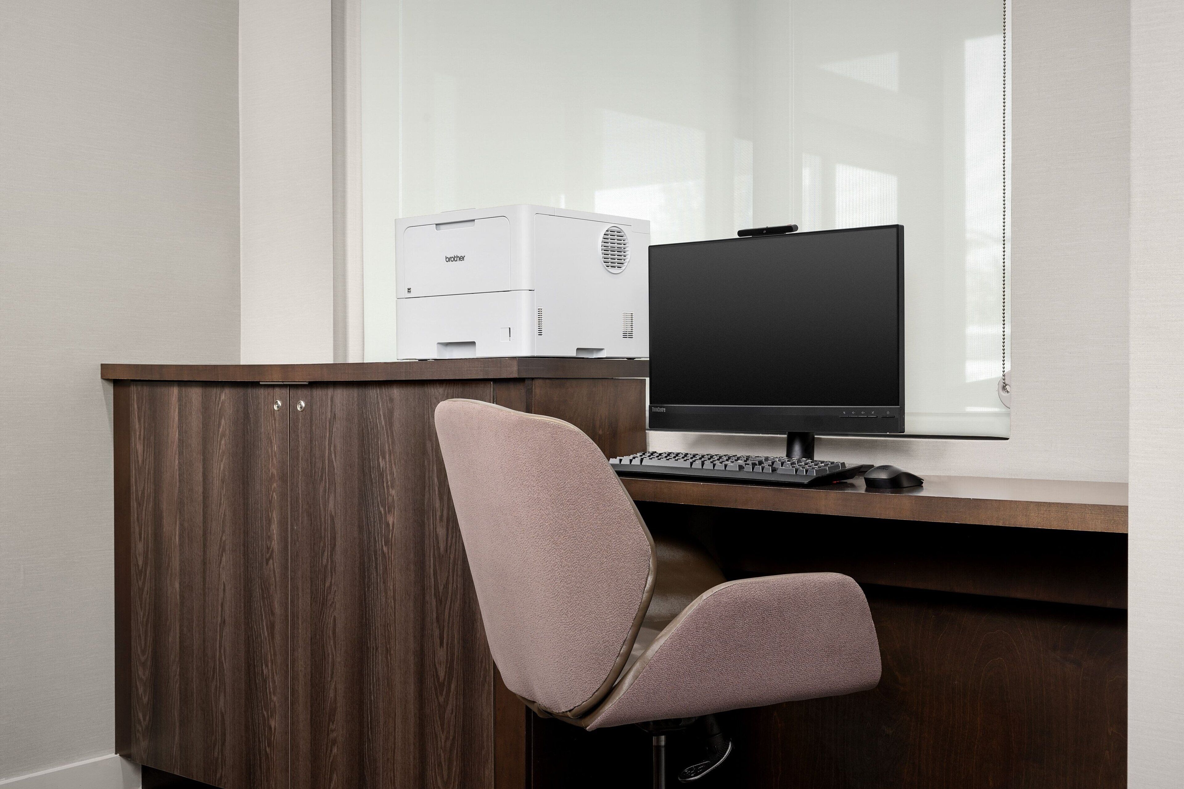 A modern office desk with a computer, a printer, and a chair.