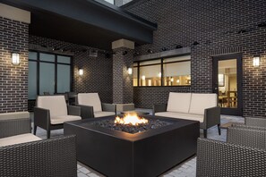 An outdoor patio area with a fire pit, wicker furniture, and a brick wall. - Residence Inn By Marriott Indianapolis Plainfield (Plainfield)