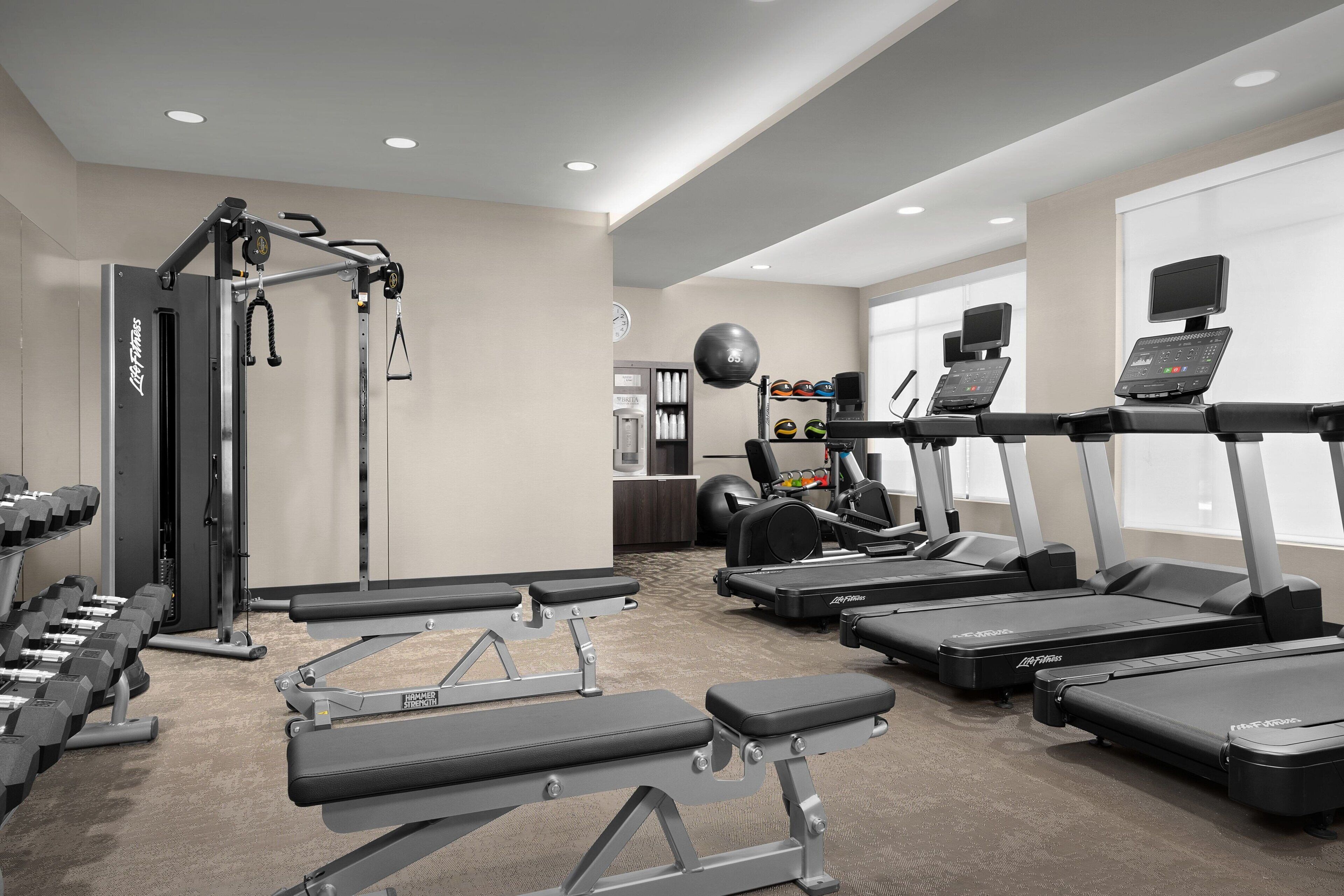 Un gimnasio con cintas de correr, mancuernas y máquinas de pesas.
