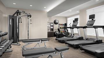 Un gimnasio con cintas de correr, mancuernas y máquinas de pesas.